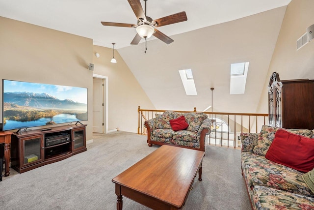 living area featuring lofted ceiling with skylight, ceiling fan, visible vents, and light colored carpet