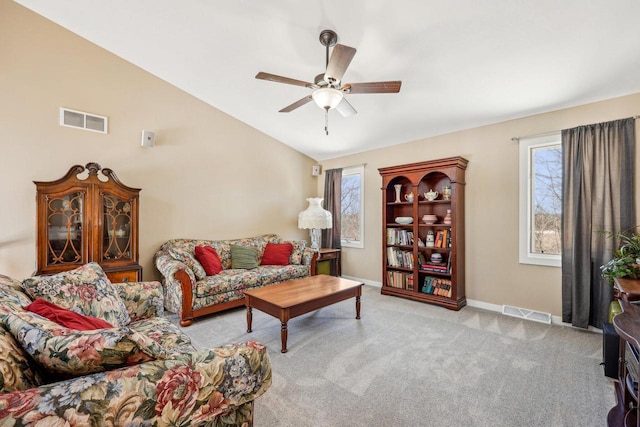 living room featuring a wealth of natural light, lofted ceiling, light carpet, and visible vents