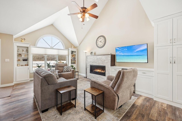 living room featuring high vaulted ceiling, ceiling fan, a stone fireplace, and wood finished floors