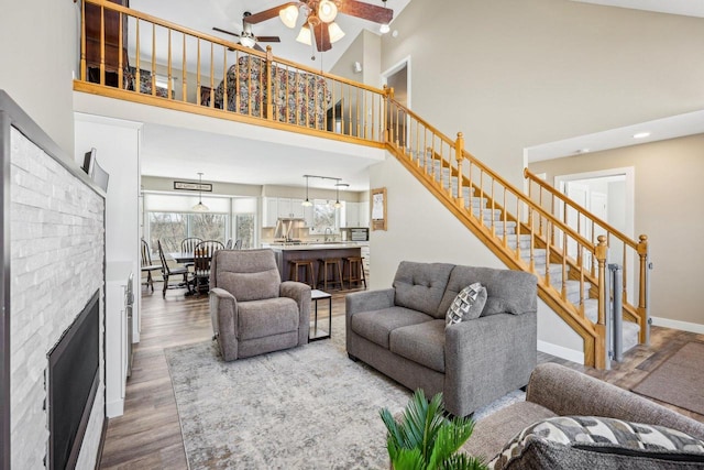 living area with a towering ceiling, stairs, baseboards, and wood finished floors