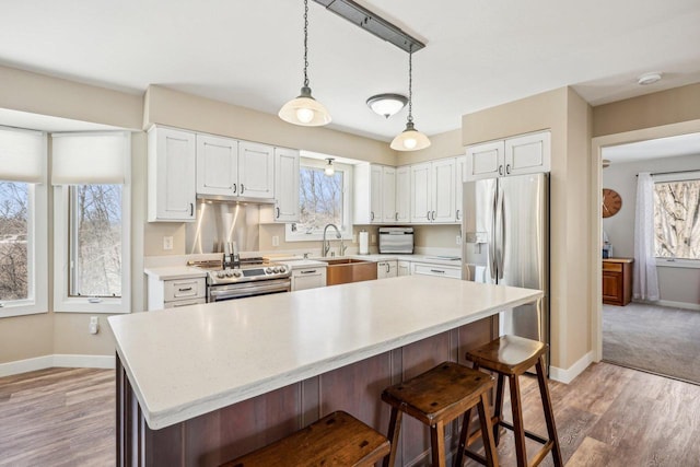 kitchen with light countertops, appliances with stainless steel finishes, a sink, and white cabinets