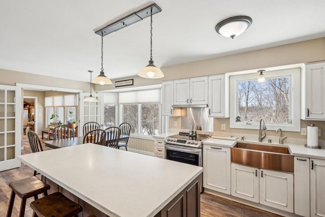 kitchen featuring light countertops, a kitchen island, a sink, and white cabinets