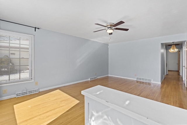 unfurnished living room featuring baseboards, visible vents, and a ceiling fan