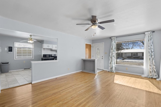 unfurnished living room with a wealth of natural light, baseboards, and light wood finished floors