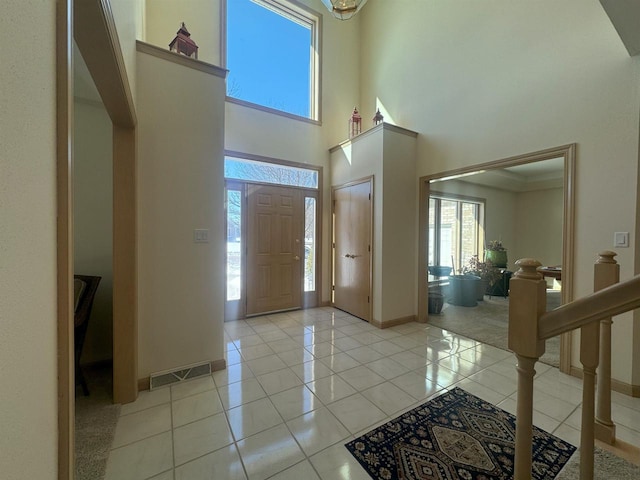 entryway with a high ceiling, visible vents, baseboards, and light tile patterned floors