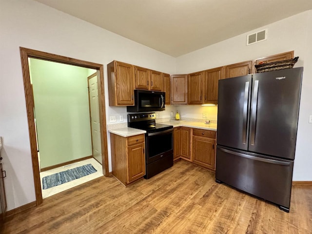 kitchen featuring light wood finished floors, visible vents, electric stove, freestanding refrigerator, and light countertops