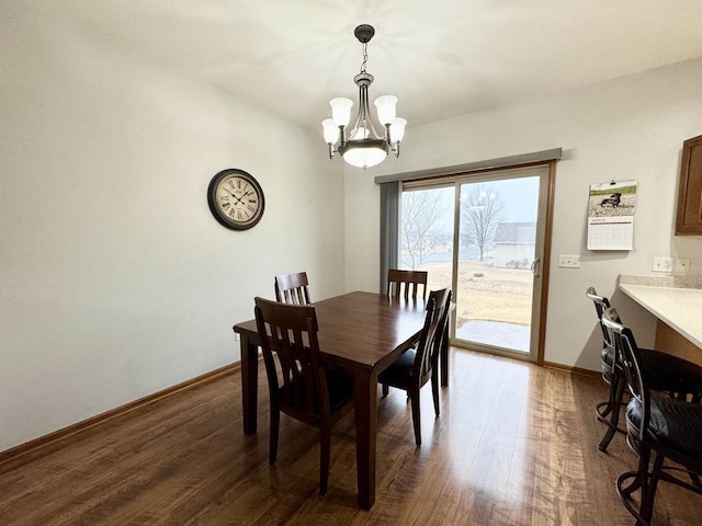 dining area featuring a notable chandelier, baseboards, and wood finished floors