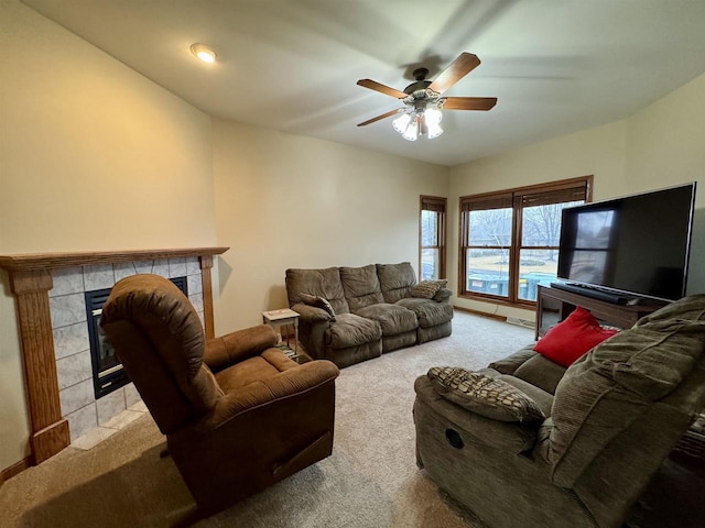 carpeted living room with a ceiling fan and a tile fireplace