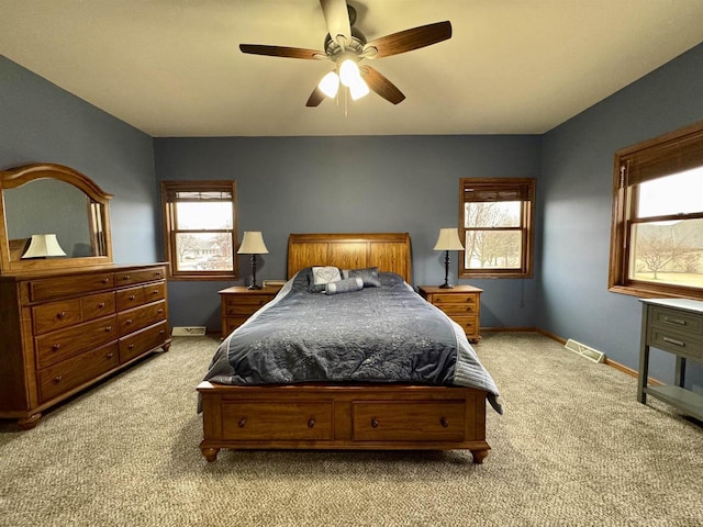 carpeted bedroom featuring ceiling fan, multiple windows, visible vents, and baseboards