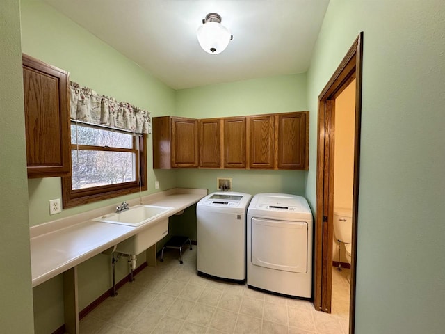 laundry room featuring washer and clothes dryer, a sink, and cabinet space