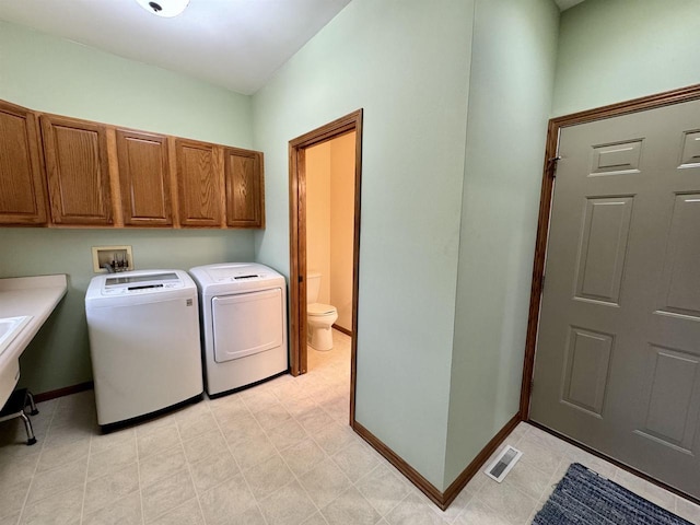 washroom featuring visible vents, washing machine and dryer, cabinet space, and baseboards