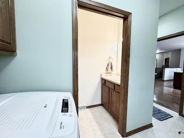 bathroom with baseboards, washer / clothes dryer, and vanity