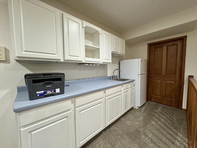 kitchen with freestanding refrigerator, light countertops, a sink, and white cabinetry