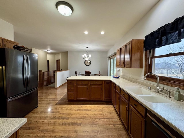 kitchen featuring a peninsula, black appliances, light countertops, and a sink