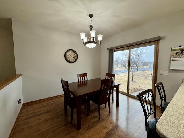 dining space with baseboards, a chandelier, and wood finished floors