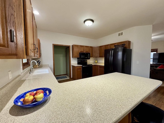 kitchen with a peninsula, a sink, visible vents, light countertops, and black appliances