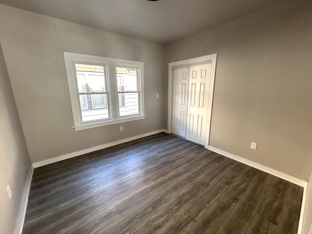 interior space featuring baseboards, dark wood finished floors, and a closet