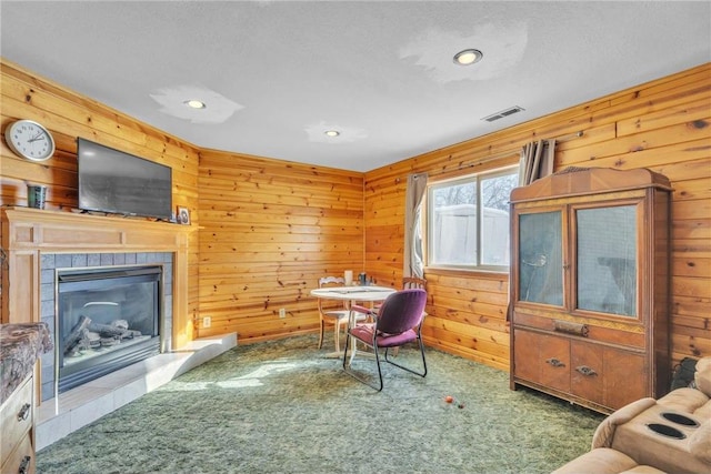 carpeted office space with wooden walls, visible vents, a textured ceiling, a fireplace, and recessed lighting