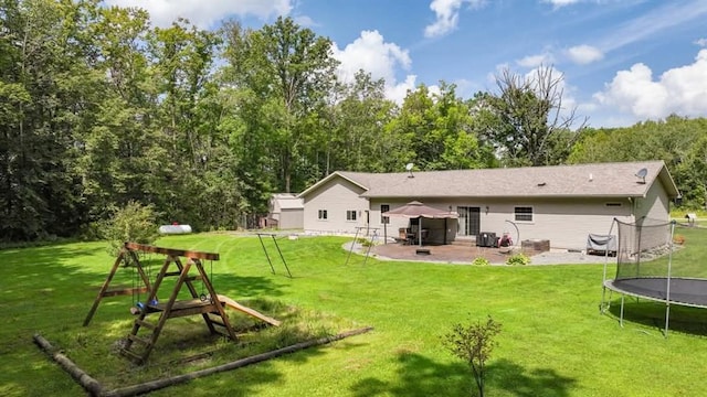 rear view of house with a patio area, a trampoline, a lawn, and a playground