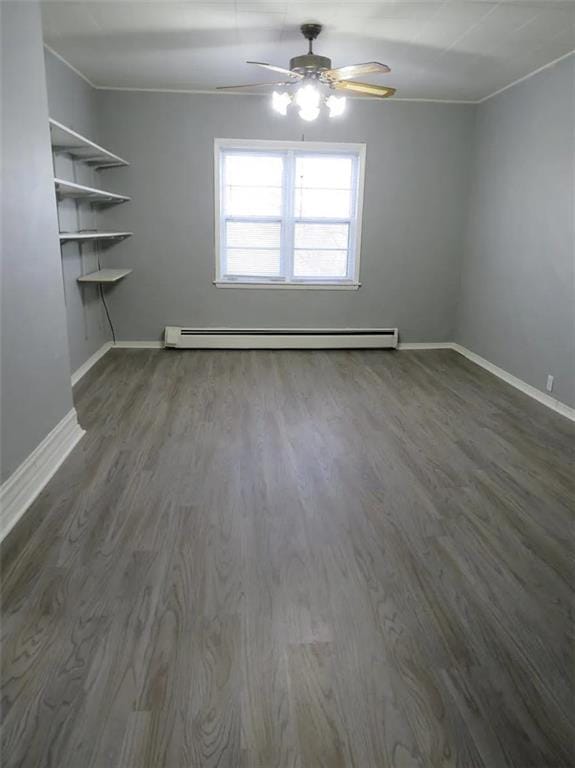 spare room featuring a baseboard radiator, baseboards, dark wood-type flooring, and ornamental molding