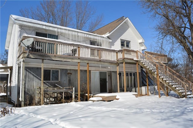 snow covered property with stairs and a wooden deck