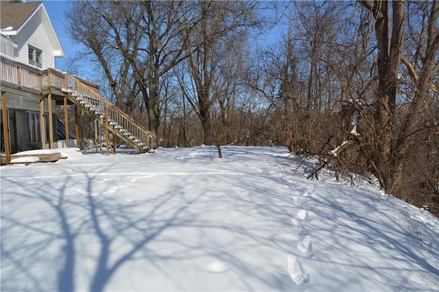 yard covered in snow with stairs and a wooden deck