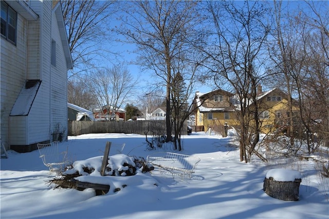 snowy yard featuring fence and a residential view