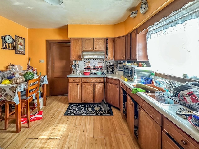 kitchen featuring brown cabinets, light wood-style flooring, tasteful backsplash, and light countertops