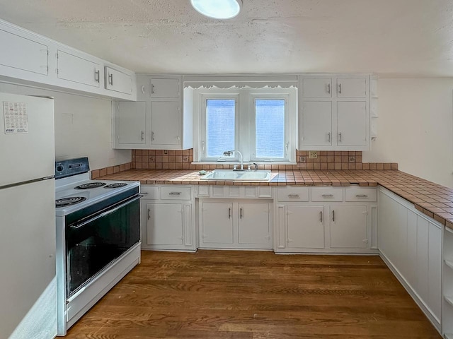 kitchen with tile countertops, white appliances, dark wood-style flooring, a sink, and white cabinetry