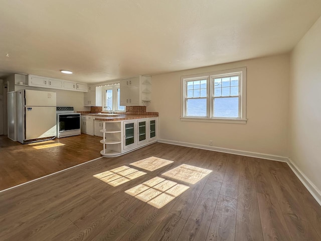 kitchen with stove, white cabinetry, freestanding refrigerator, open shelves, and dark wood finished floors