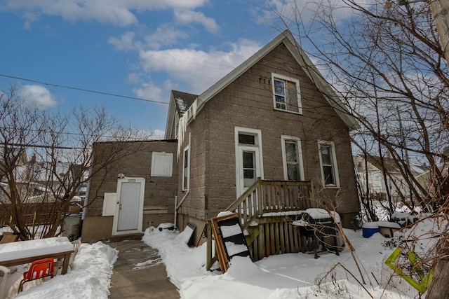 snow covered back of property with brick siding