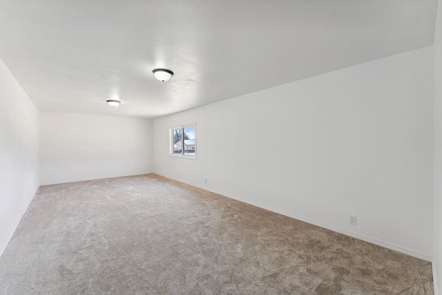 spare room with baseboards and carpet