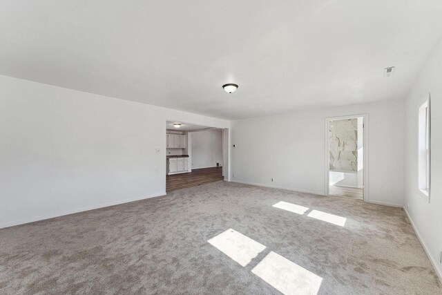 empty room featuring visible vents, carpet floors, and baseboards
