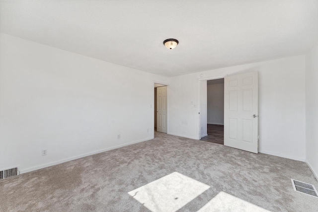 carpeted empty room featuring visible vents and baseboards