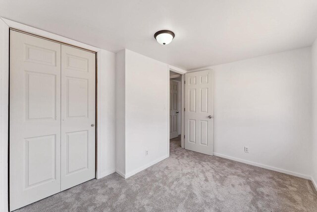 unfurnished bedroom featuring carpet, baseboards, and a closet
