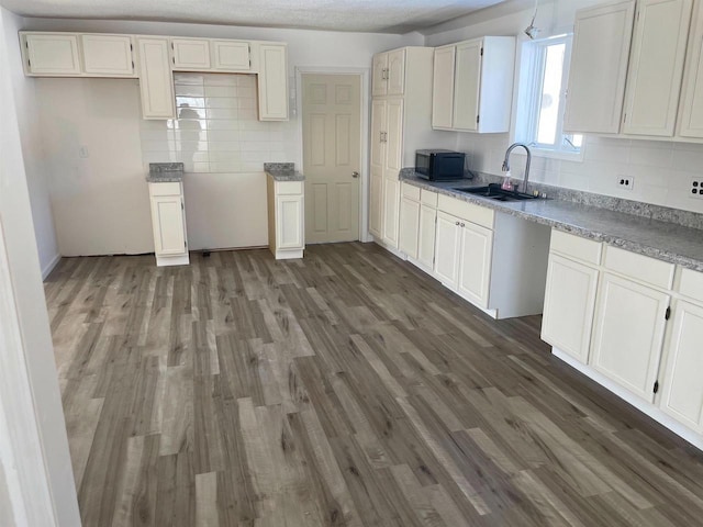 kitchen with a sink, tasteful backsplash, dark wood finished floors, and black microwave