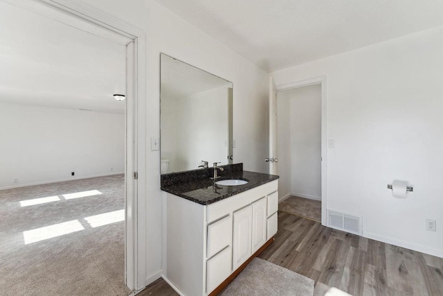 bathroom with vanity, wood finished floors, baseboards, and visible vents