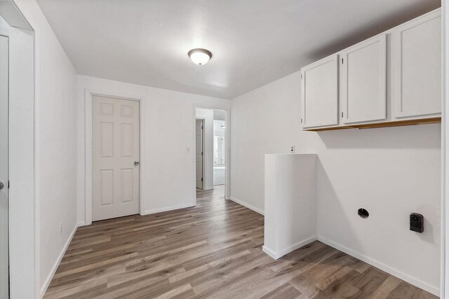 laundry room featuring cabinet space, baseboards, and light wood-type flooring