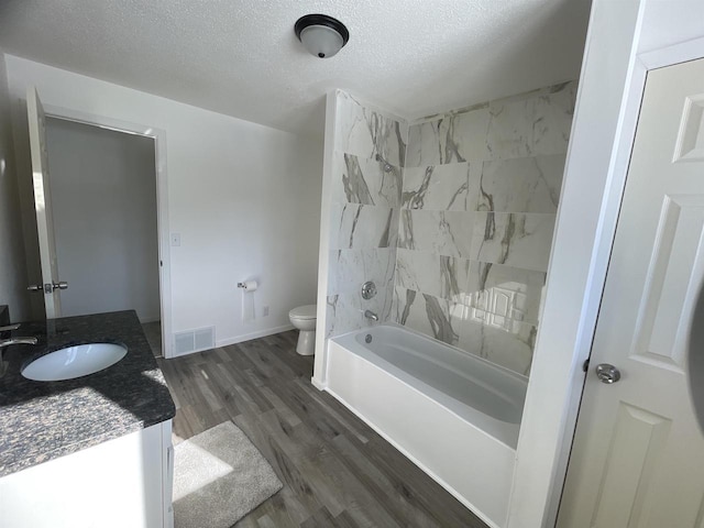 bathroom with visible vents, toilet, vanity, wood finished floors, and a textured ceiling