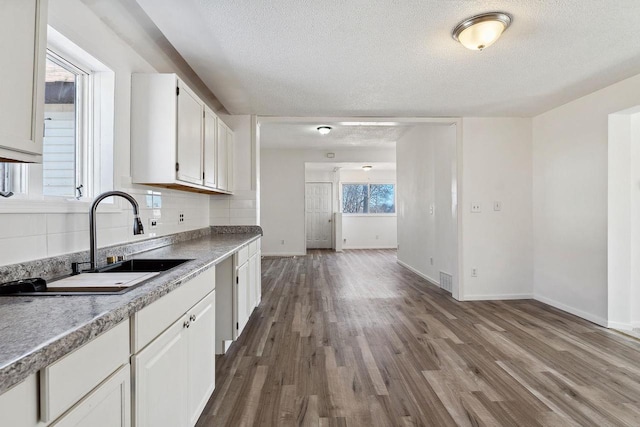 kitchen with tasteful backsplash, dark wood finished floors, white cabinets, a textured ceiling, and a sink