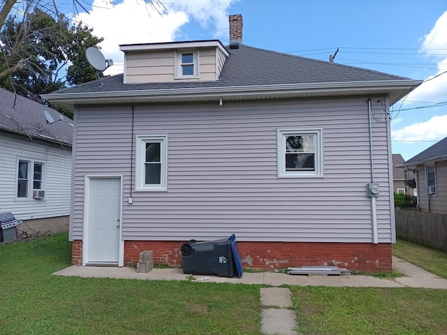 back of house with a shingled roof, a lawn, a chimney, and cooling unit