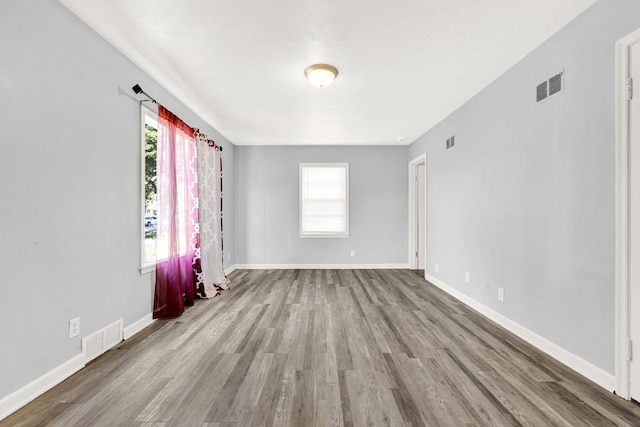 empty room featuring baseboards, visible vents, and light wood finished floors