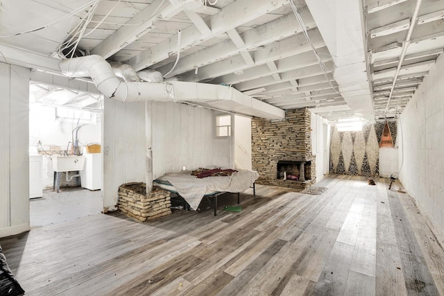 unfinished basement with washer / clothes dryer, a fireplace, and wood finished floors
