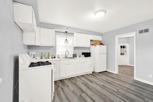 kitchen featuring light countertops, visible vents, hanging light fixtures, a sink, and white appliances