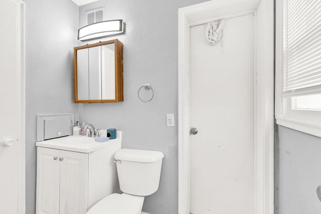 half bath with visible vents, vanity, and toilet