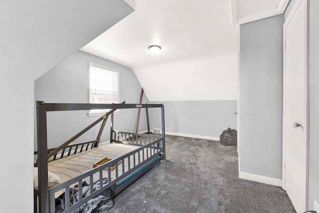 bedroom with lofted ceiling, dark carpet, visible vents, and baseboards
