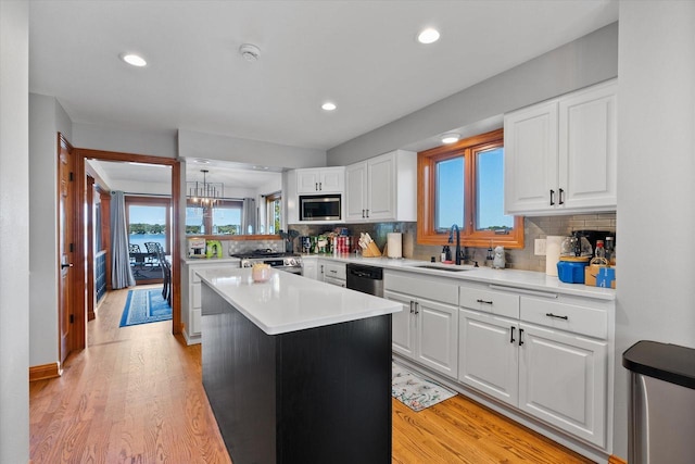 kitchen featuring white cabinets, light countertops, a sink, and a center island