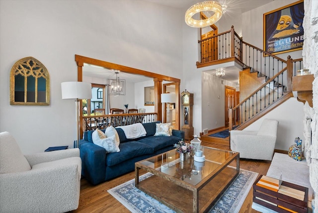 living area featuring an inviting chandelier, baseboards, stairway, and wood finished floors