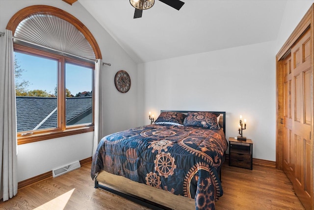 bedroom with light wood-style flooring, visible vents, vaulted ceiling, and baseboards