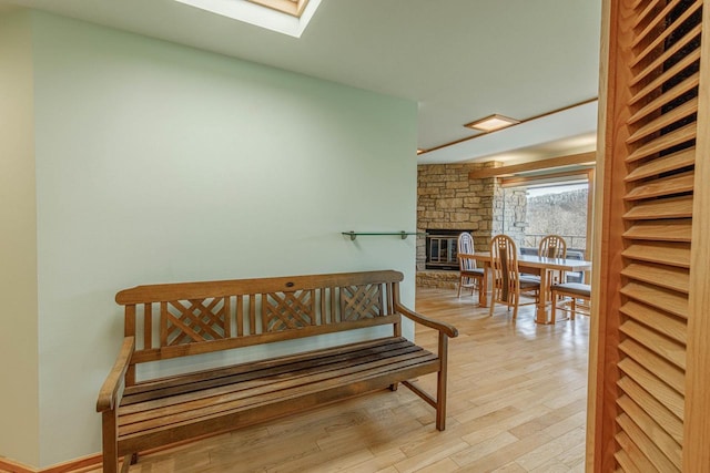 living area featuring light wood-style floors, a fireplace, and a skylight